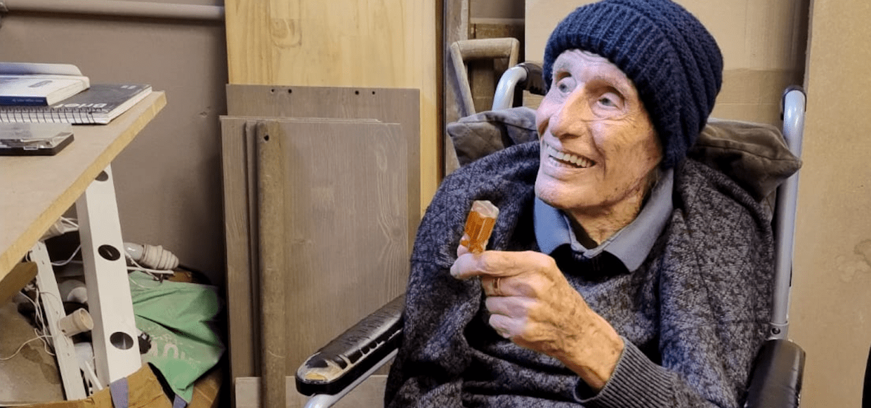 Homem idoso sorri e segura ferramenta